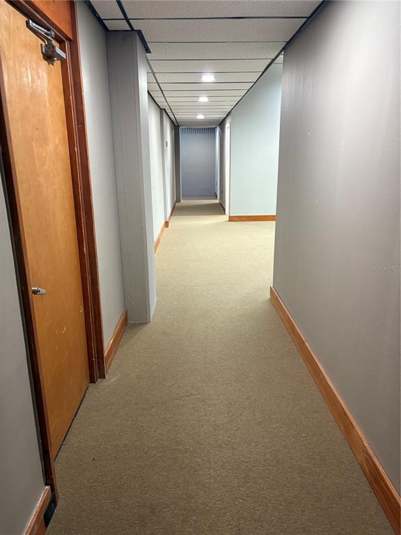 A long, carpeted hallway features light gray walls, wood trim, and a drop ceiling — 375 CENTRAL AVENUE, WINTER HAVEN, FL