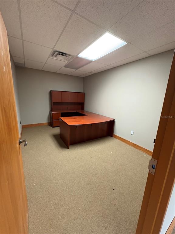 An office room features a large wooden desk, beige carpeting, and a drop ceiling — 375 CENTRAL AVENUE, WINTER HAVEN, FL