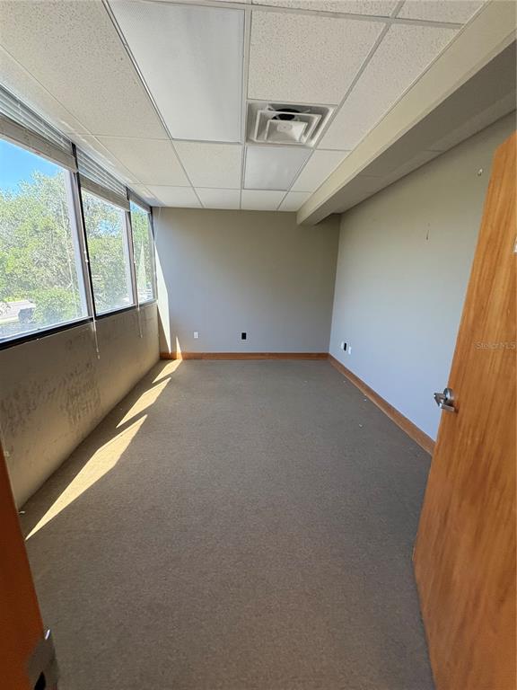 An empty office with gray walls, beige carpet, a drop ceiling, and large windows — 375 CENTRAL AVENUE, WINTER HAVEN, FL