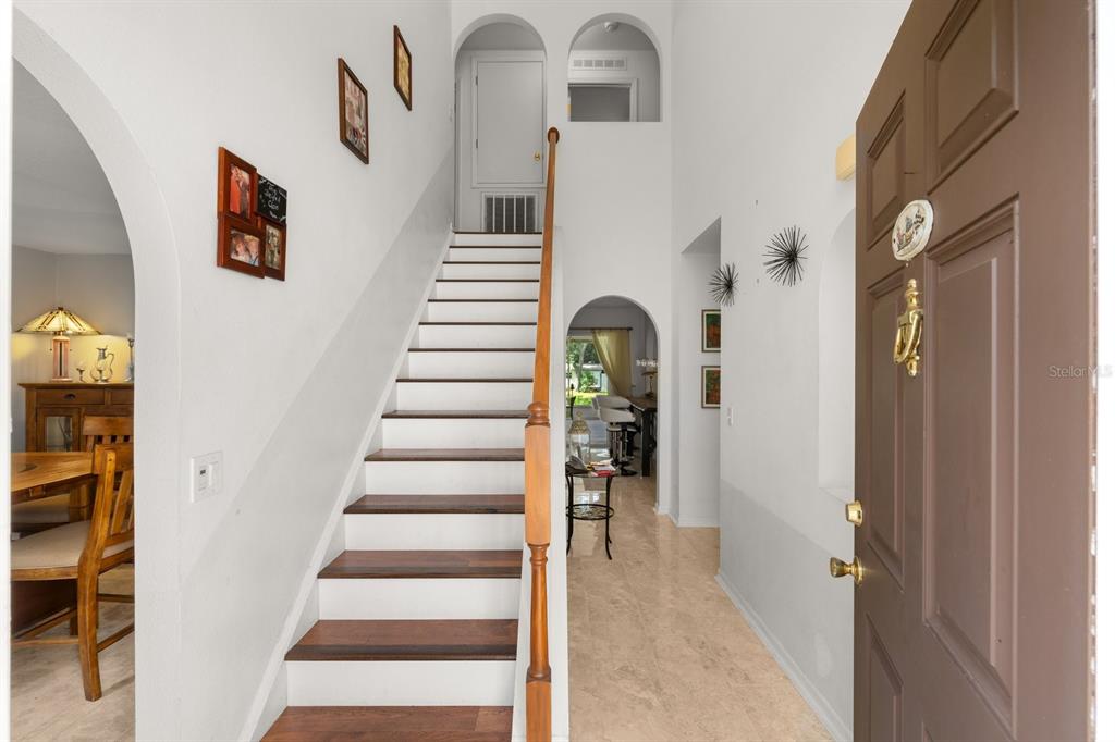 An entryway features a staircase with wood treads, tile flooring, and arched doorways — 7651 LAKE ANDREA CIRCLE, MOUNT DORA, FL