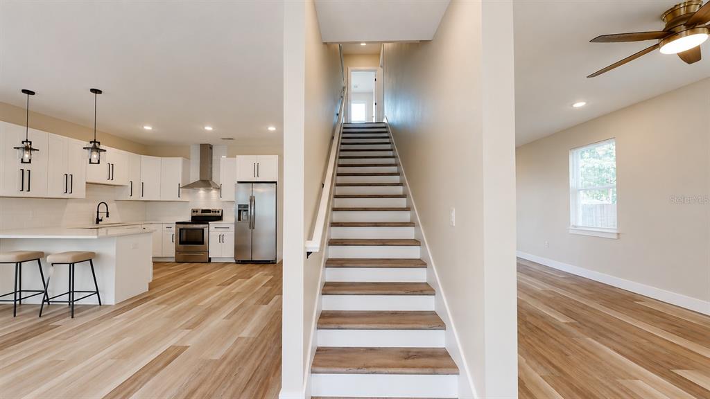 A kitchen with white cabinets and a central staircase with wood-toned treads — 4710 21ST STREET N, ST PETERSBURG, FL