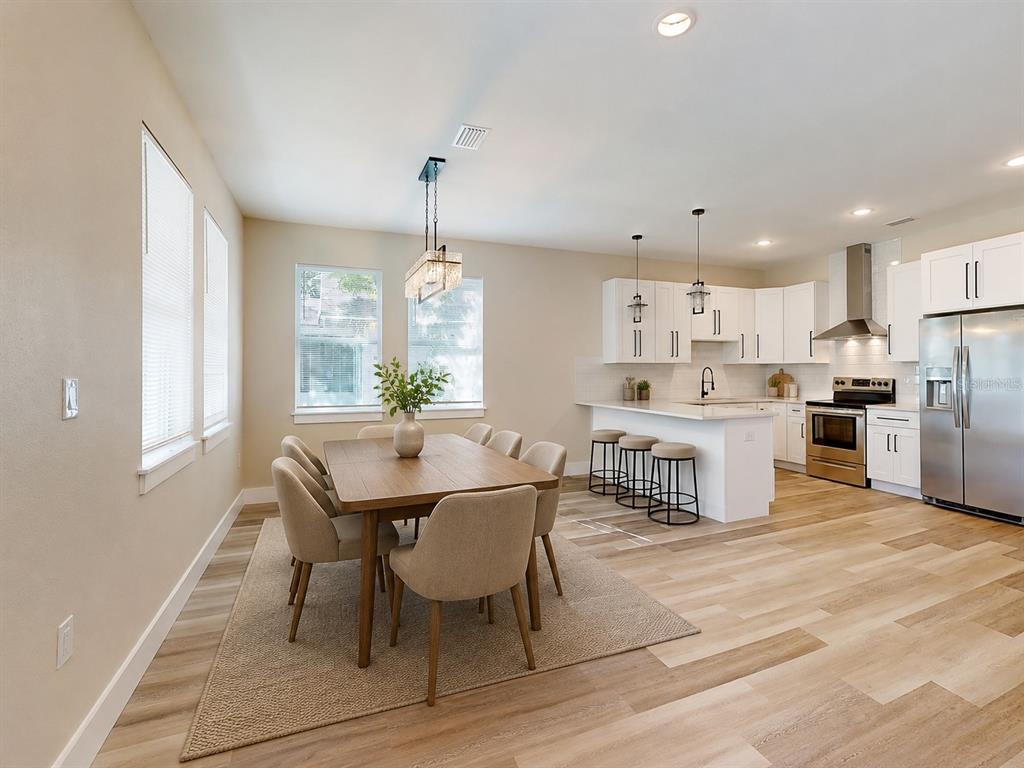 A dining area with a wooden table and chairs sits adjacent to a modern white kitchen — 4710 21ST STREET N, ST PETERSBURG, FL