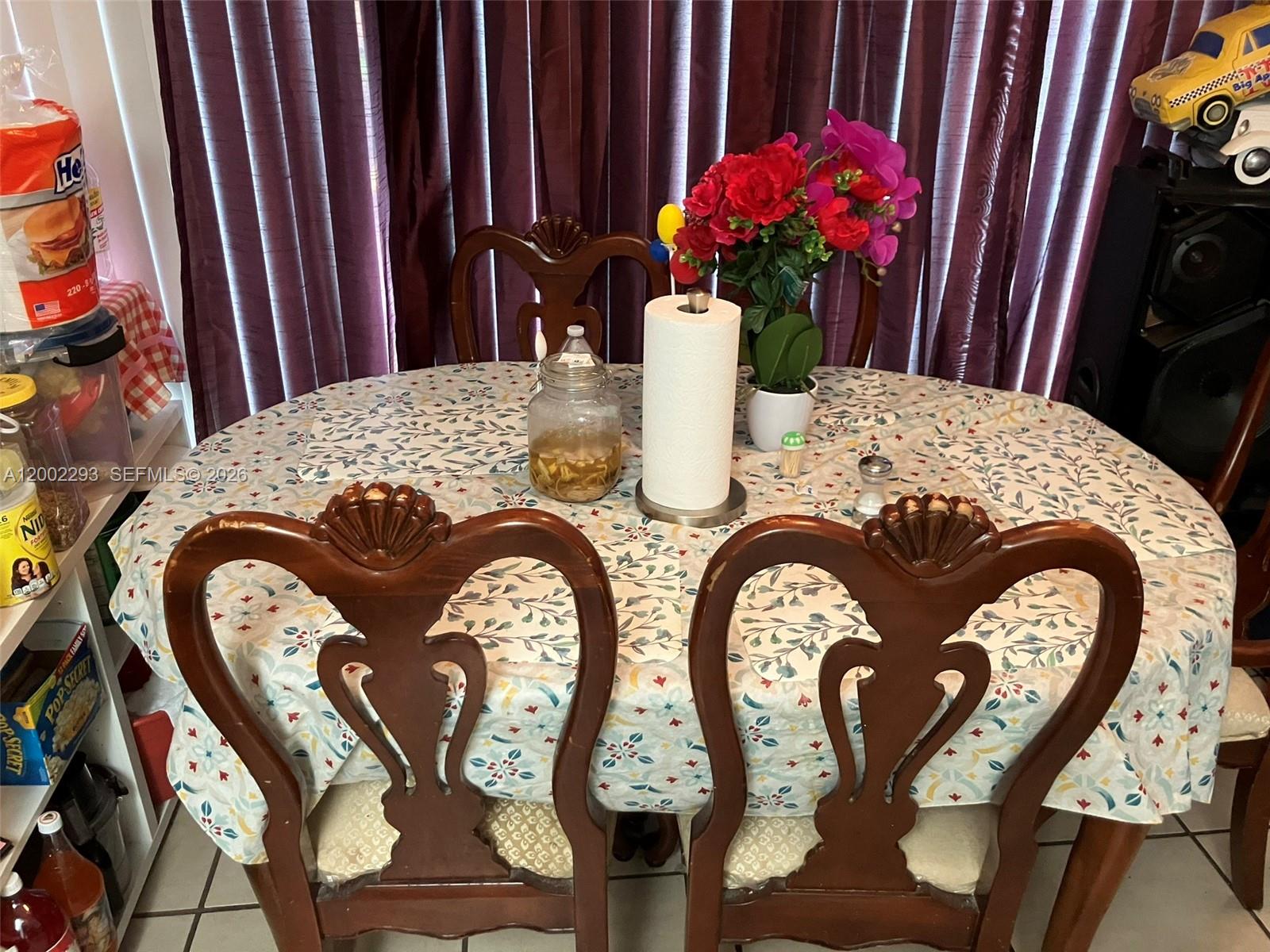 A dining area features a round table with a patterned tablecloth and four wooden chairs — 9311 SW 4th St # 104B, Miami FL 33174, MIAMI, FL