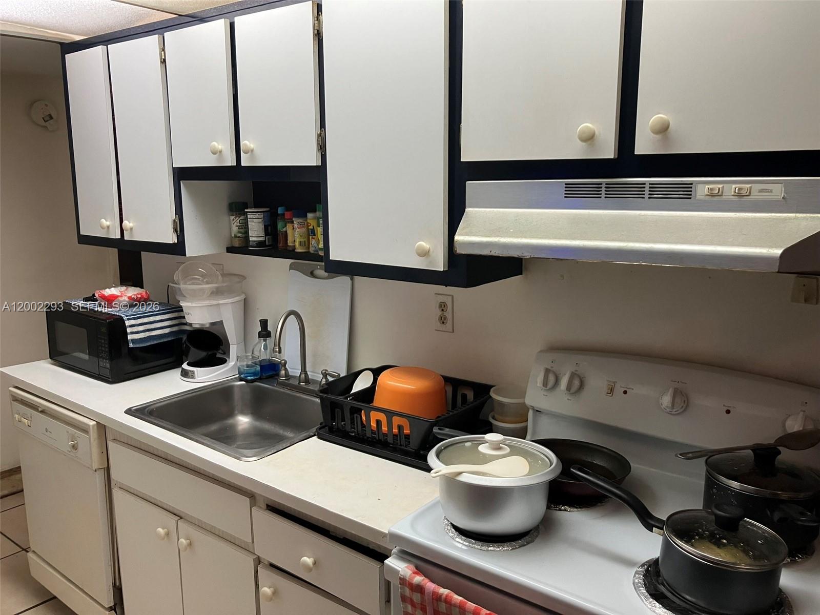 A kitchen features white cabinets with dark trim, a stainless steel sink, and white appliances — 9311 SW 4th St # 104B, Miami FL 33174, MIAMI, FL