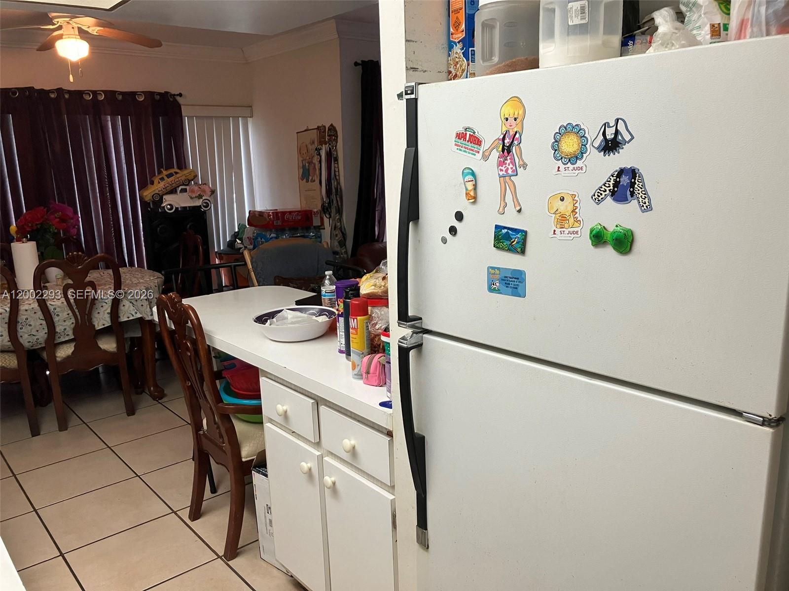 A white refrigerator stands in a kitchen next to a dining area with a table — 9311 SW 4th St # 104B, Miami FL 33174, MIAMI, FL
