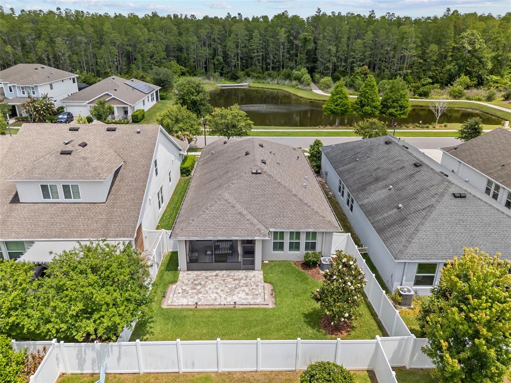 An aerial view shows a house with a screened patio, paver patio, and fenced yard — 15180 RENAISSANCE AVENUE, ODESSA, FL