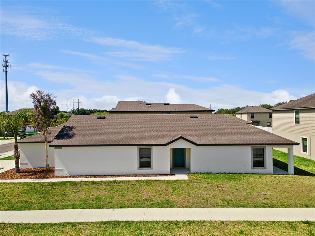 A single-story white house with a brown shingled roof and a teal front door — 6535 BAIKAL PLACE, LAKELAND, FL