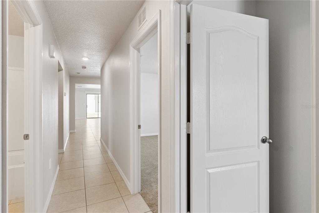 A hallway with tile flooring leads toward a bright room with a sliding glass door — 6535 BAIKAL PLACE, LAKELAND, FL