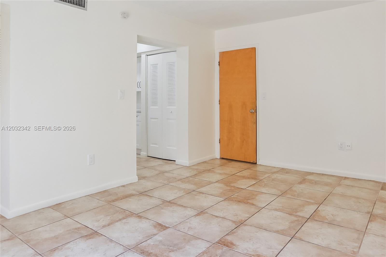 An empty room features white walls, tan tile flooring, a wooden door, and a closet — 11521 SW 109th Rd # 10A, Miami FL 33176, MIAMI, FL