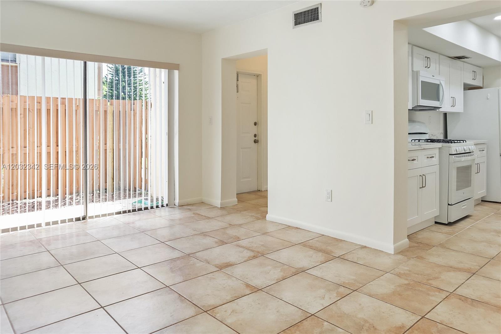 A tiled dining area features a sliding glass door and an adjacent white kitchen — 11521 SW 109th Rd # 10A, Miami FL 33176, MIAMI, FL