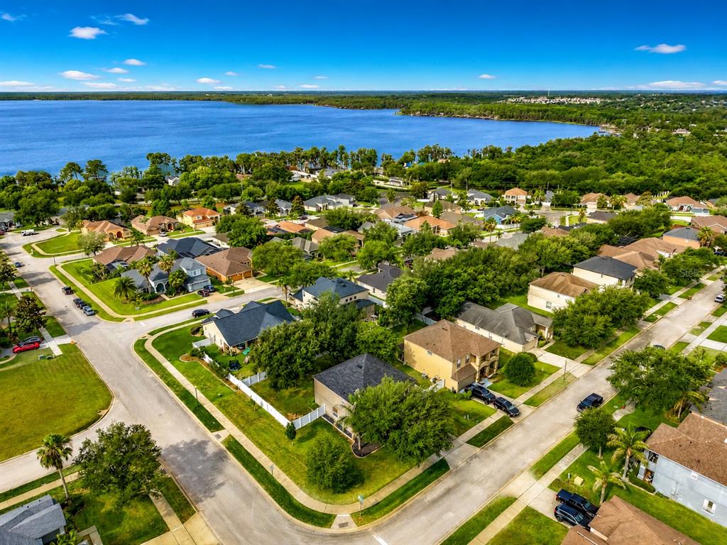 An aerial view shows a suburban neighborhood with houses, green lawns, and a large lake — 12912 CLOVERDALE LANE, CLERMONT, FL