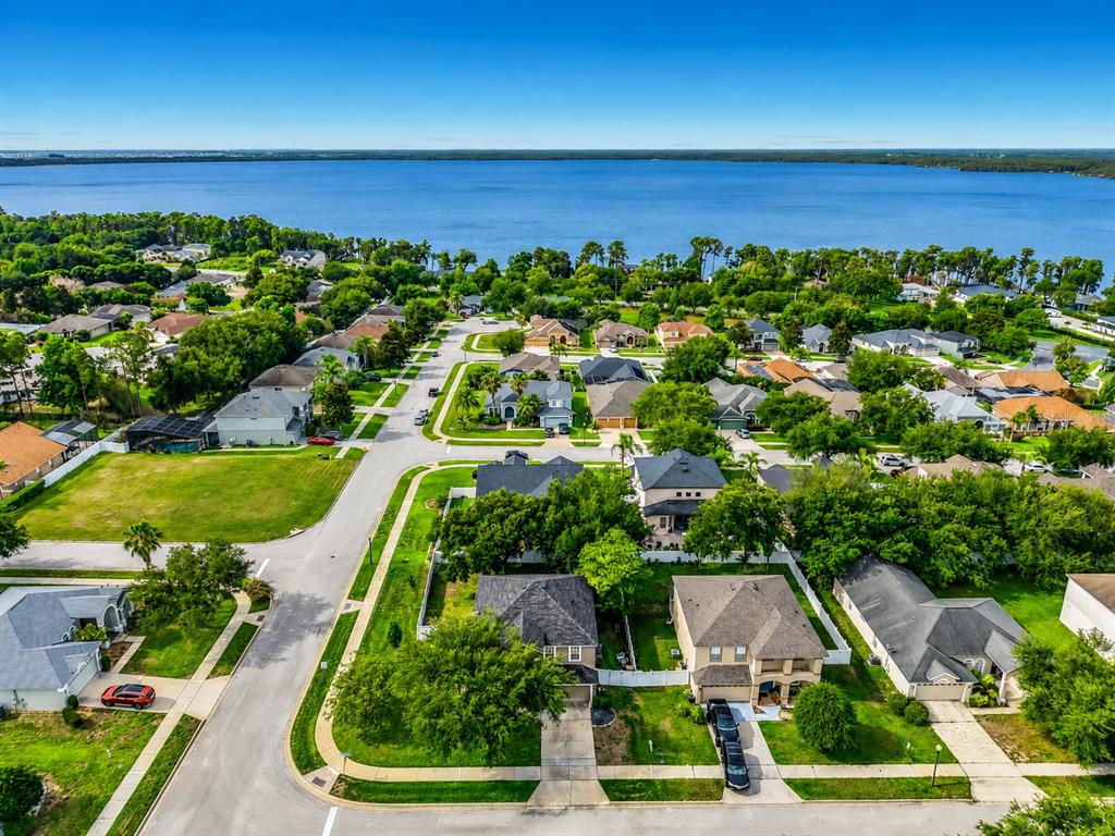 An aerial view shows a suburban neighborhood with houses, green lawns, and a large lake — 12912 CLOVERDALE LANE, CLERMONT, FL