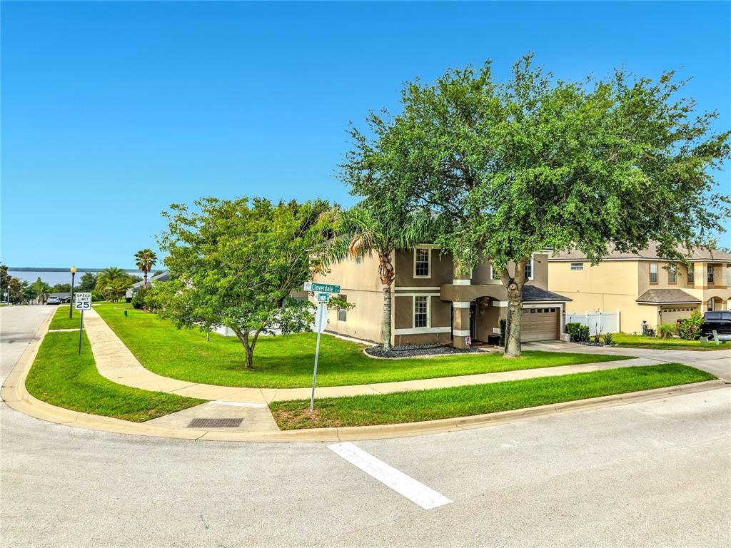 A two-story house with a tan exterior and a two-car garage sits on a corner — 12912 CLOVERDALE LANE, CLERMONT, FL
