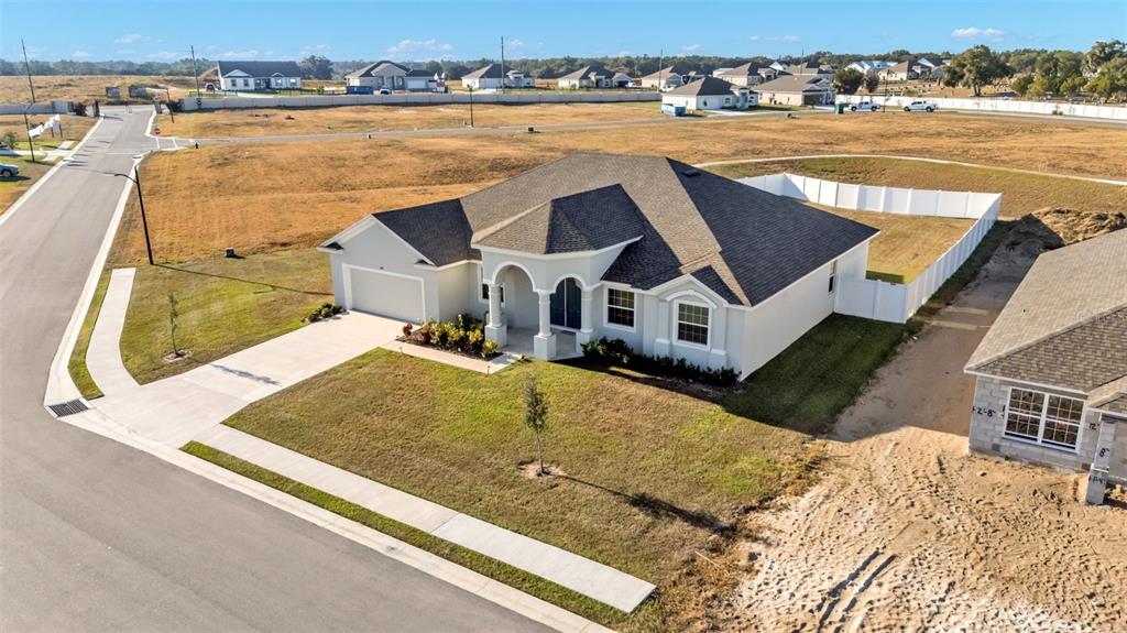 An aerial view shows a single-story suburban house with a driveway and white vinyl fencing — 1029 BERGAMOT DRIVE, BARTOW, FL