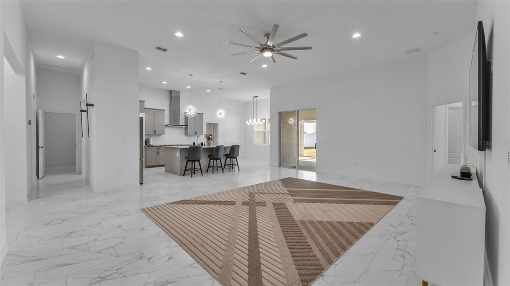 An open-concept living room and kitchen featuring white marble-look tile flooring and a geometric rug — 1029 BERGAMOT DRIVE, BARTOW, FL