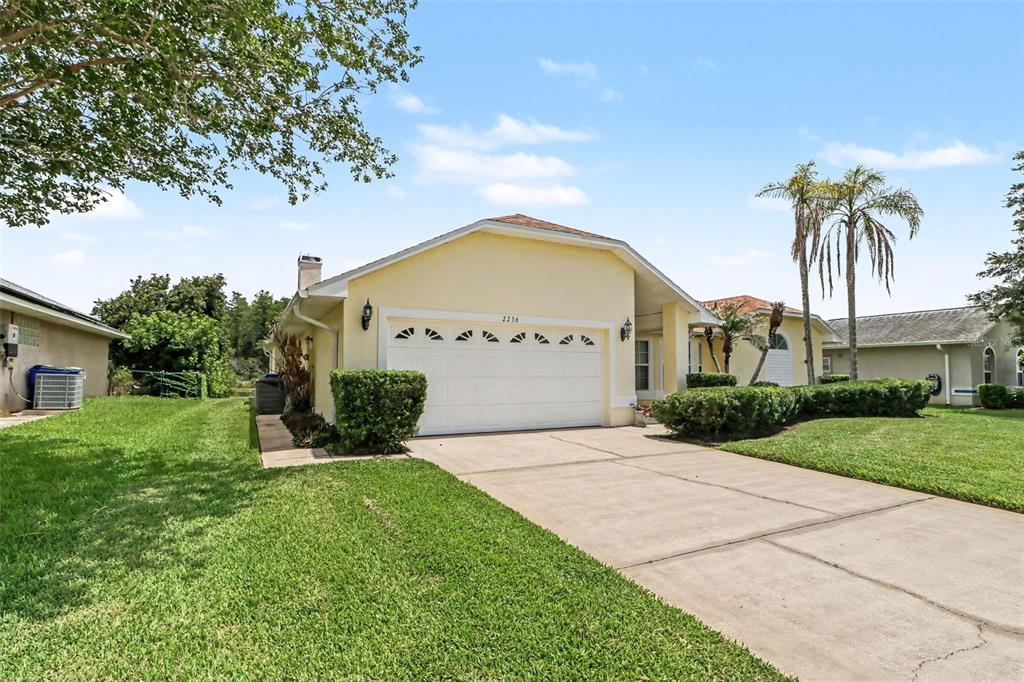 A single-story house with a yellow exterior, a two-car garage, and a concrete driveway — 2236 SUMMER RAYE COURT, ST CLOUD, FL