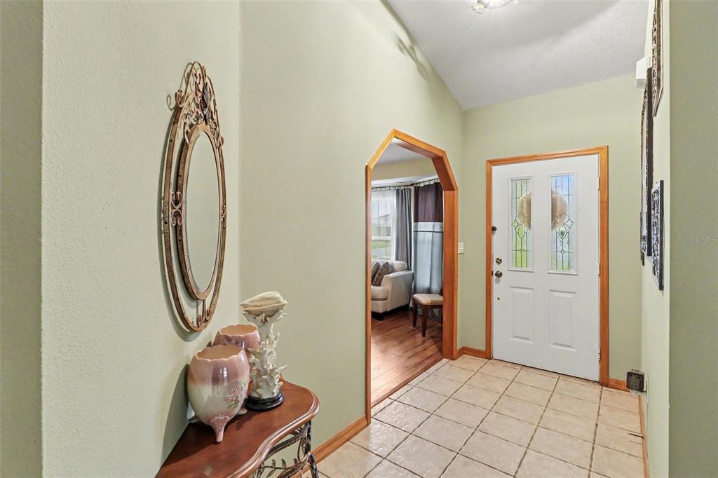 A tiled entryway features a wooden console table, an oval mirror, and an arched doorway — 2236 SUMMER RAYE COURT, ST CLOUD, FL