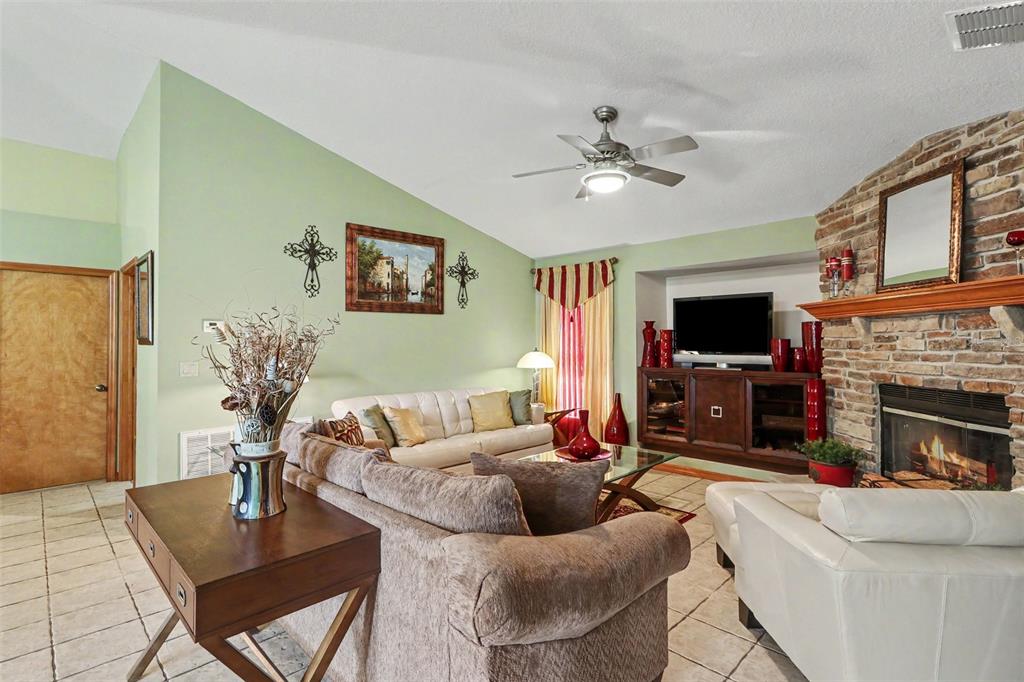 A living room features a stone fireplace, vaulted ceilings, tile floors, and a ceiling fan — 2236 SUMMER RAYE COURT, ST CLOUD, FL