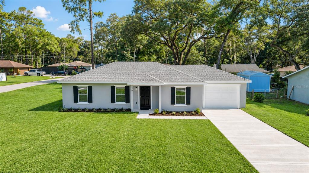 A single-story gray house with a white garage, black shutters, and a front lawn — 16 REDWOOD TRACE, OCALA, FL