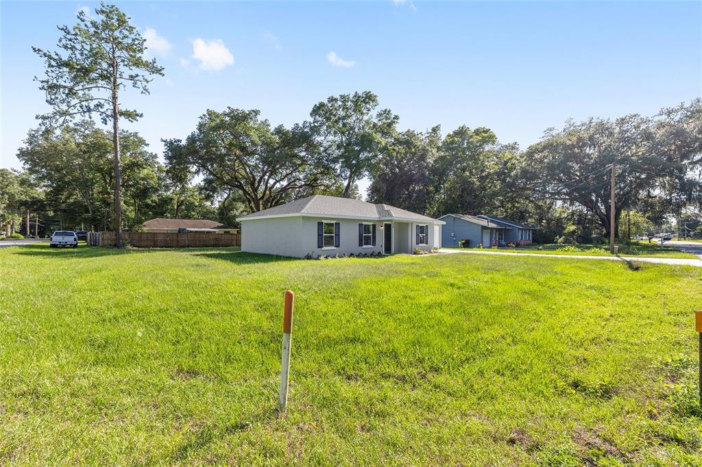 A single-story house with a gray exterior sits on a large, grassy residential lot — 16 REDWOOD TRACE, OCALA, FL