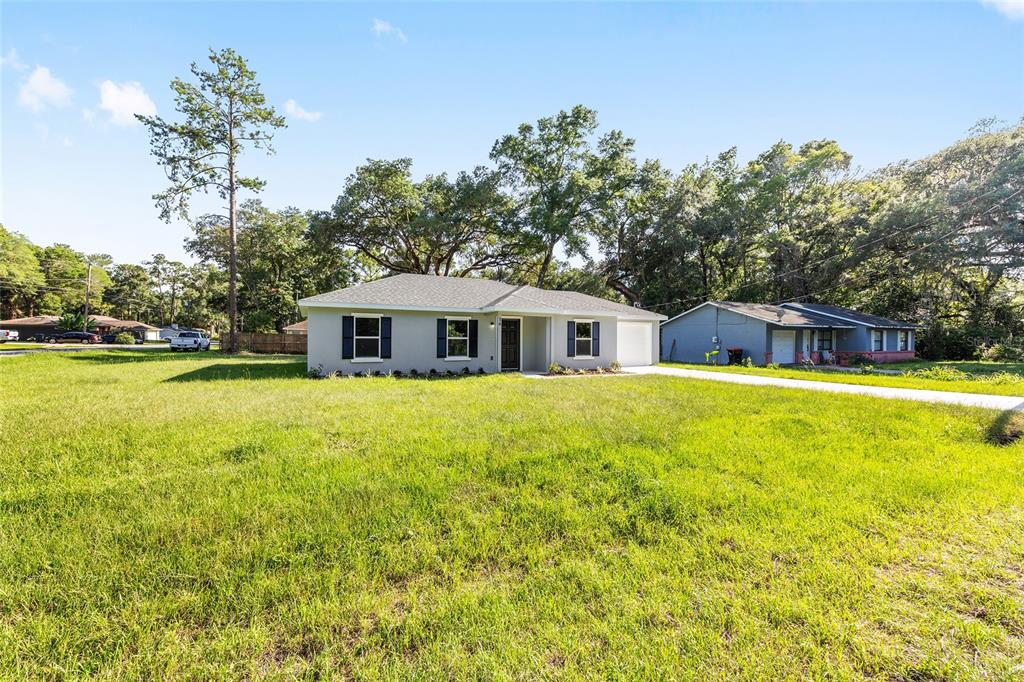 A single-story house with a gray exterior, dark shutters, and a large front lawn — 16 REDWOOD TRACE, OCALA, FL
