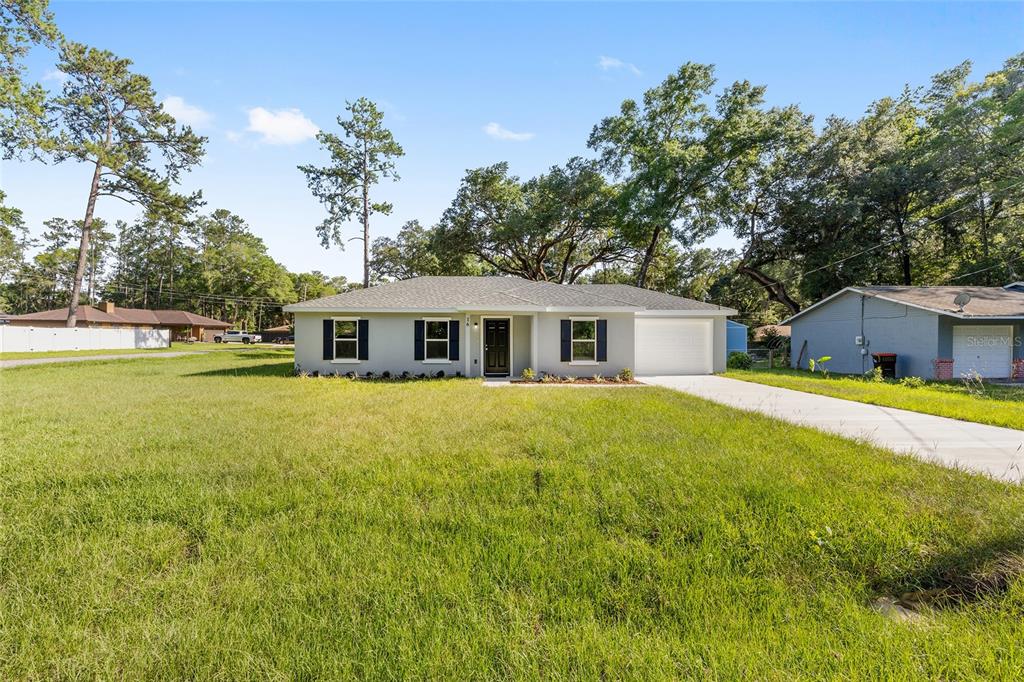 A single-story house with a gray exterior, black shutters, and a front-facing garage — 16 REDWOOD TRACE, OCALA, FL