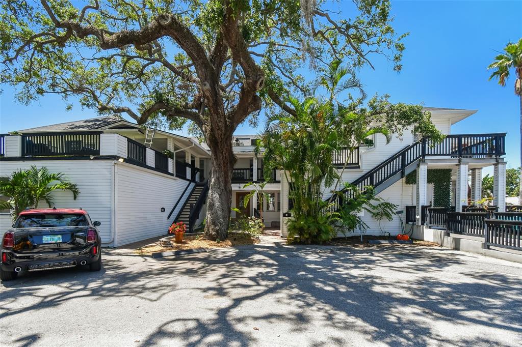 A two-story white building with black railings and an exterior staircase stands behind a car — 454 MAIN STREET, SAFETY HARBOR, FL