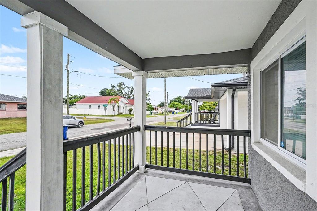 A living room features a white front door, light wood-look flooring, and modern neutral furniture — 2619 W ST CONRAD, TAMPA, FL