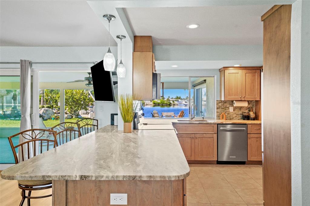A kitchen with wood cabinets, stone countertops, and a view of the water outside — 3711 FLORAMAR TERRACE, NEW PORT RICHEY, FL
