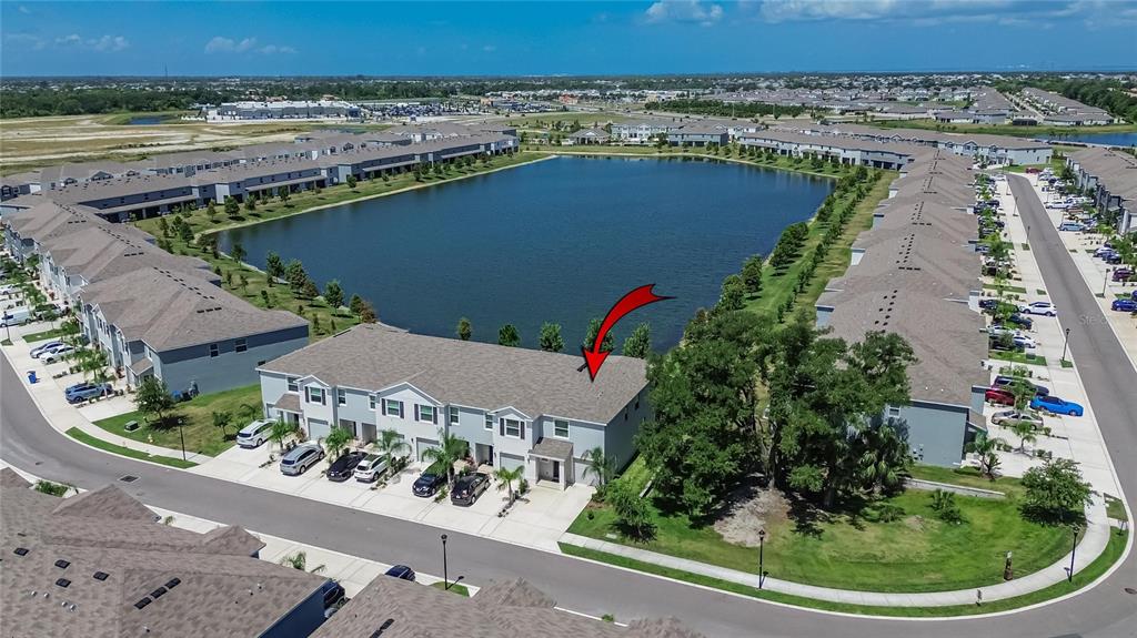 An aerial view shows a multi-unit townhouse building situated next to a large pond — 331 MANGROVE SHADE CIRCLE, APOLLO BEACH, FL