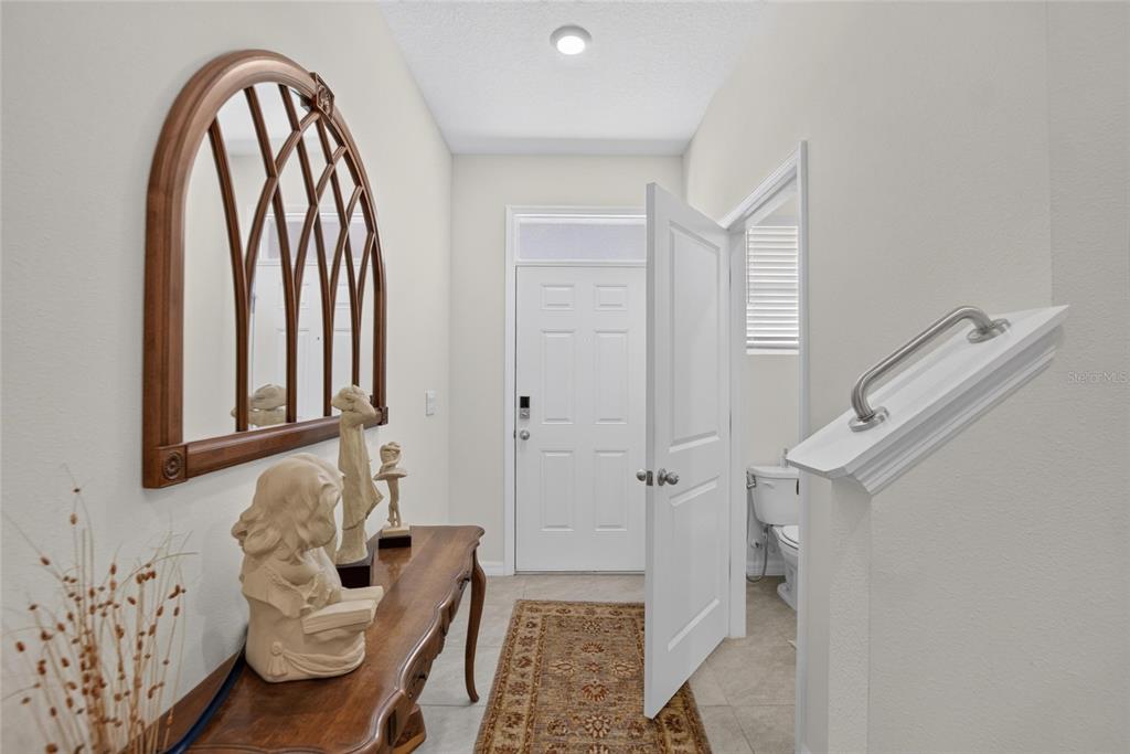 An entryway features a wooden console table, an arched mirror, and a door to a bathroom — 331 MANGROVE SHADE CIRCLE, APOLLO BEACH, FL