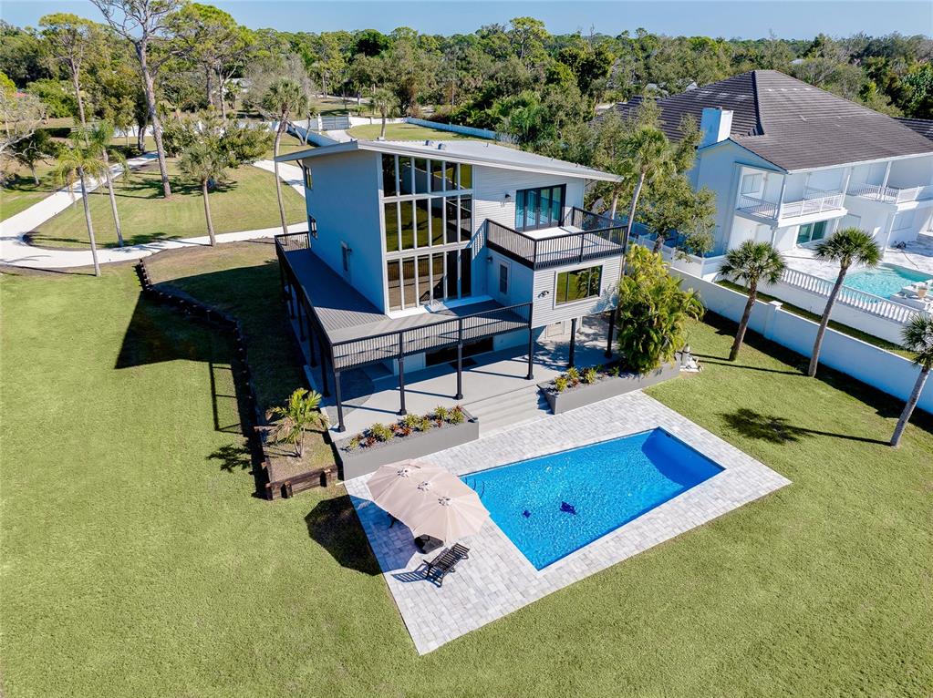 An aerial view of a modern two-story house with a pool and a large lawn — 1089 BAYSHORE DRIVE, ENGLEWOOD, FL