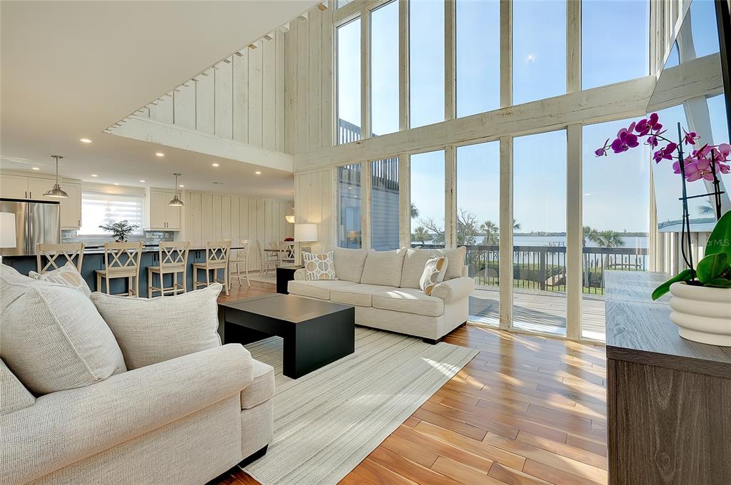 A living room with high ceilings, floor-to-ceiling windows, and a view of the water — 1089 BAYSHORE DRIVE, ENGLEWOOD, FL