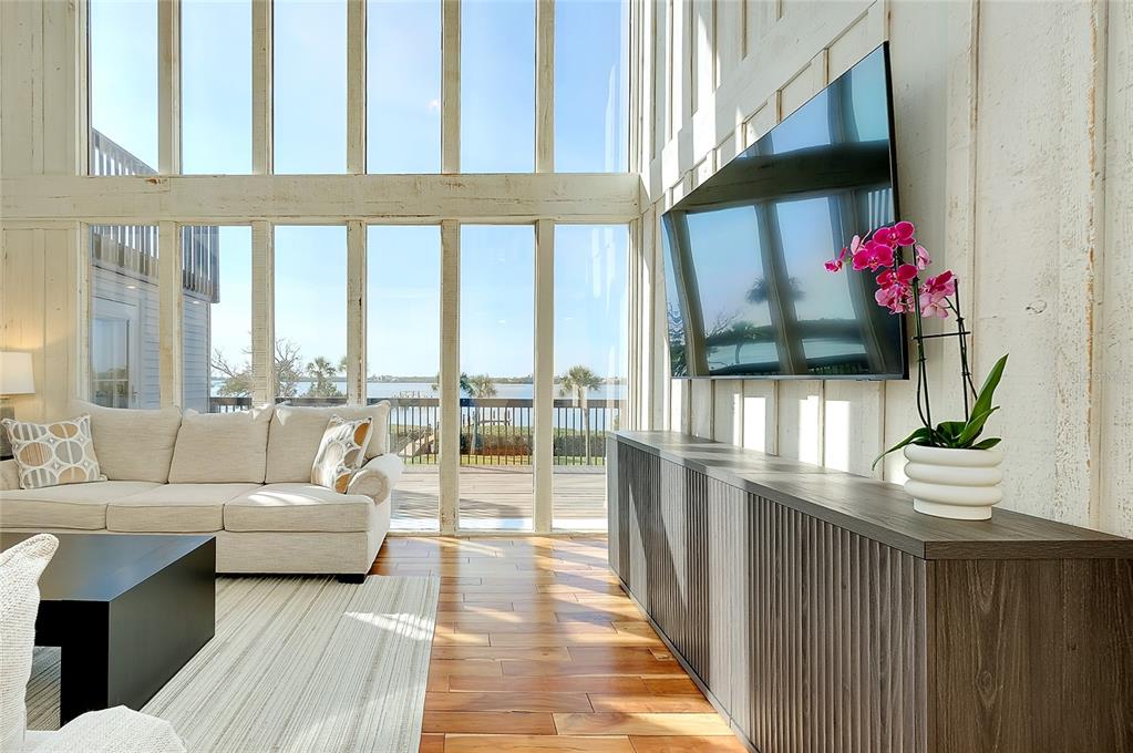 A living room features floor-to-ceiling windows, a wall-mounted television, and a wooden media console — 1089 BAYSHORE DRIVE, ENGLEWOOD, FL