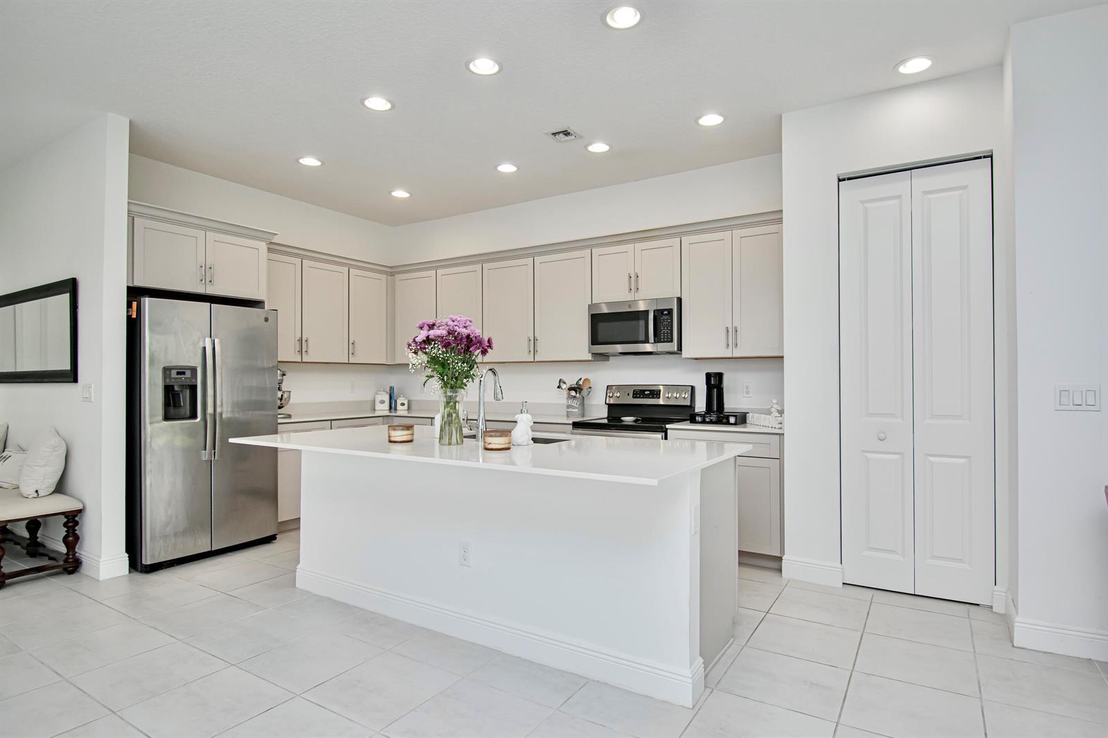 A modern kitchen features light gray cabinets, stainless steel appliances, and a white quartz island — 16420 Sandy Shore Drive, Loxahatchee FL 33470, LOXAHATCHEE, FL
