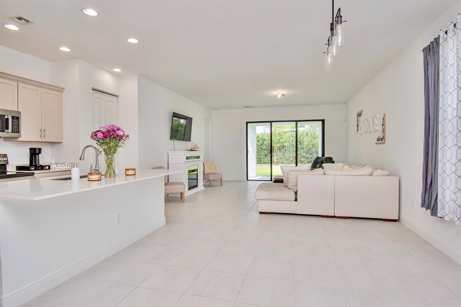 A bright open-concept living area features a kitchen with white counters and a beige sofa — 16420 Sandy Shore Drive, Loxahatchee FL 33470, LOXAHATCHEE, FL