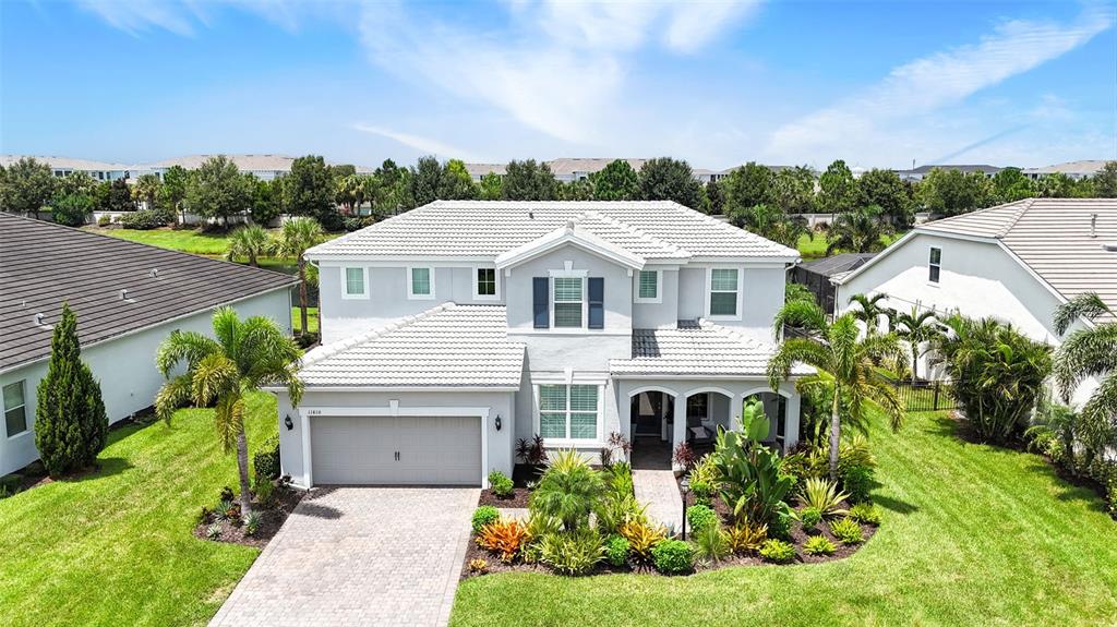 An aerial view of a two-story suburban house with a tiled roof and landscaped yard — 11810 BLUE HILL TRAIL, BRADENTON, FL