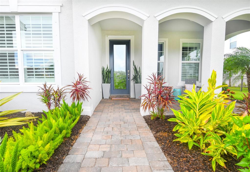 A paved walkway leads to the front entrance of a white house with arched alcoves — 11810 BLUE HILL TRAIL, BRADENTON, FL