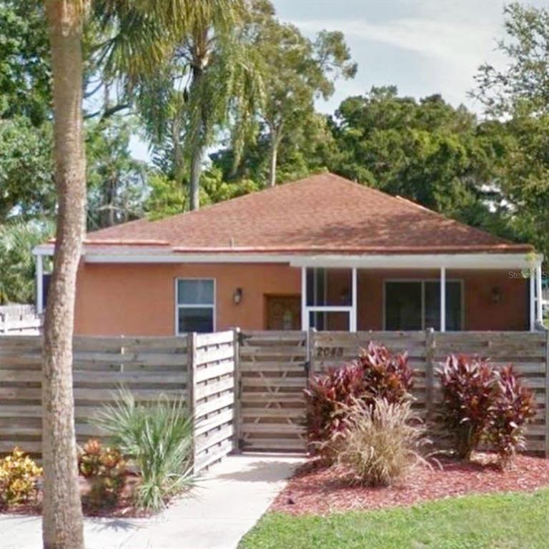 A single-story house with a brown roof and orange exterior sits behind a wooden fence — 2043 ROSELAWN STREET, SARASOTA, FL