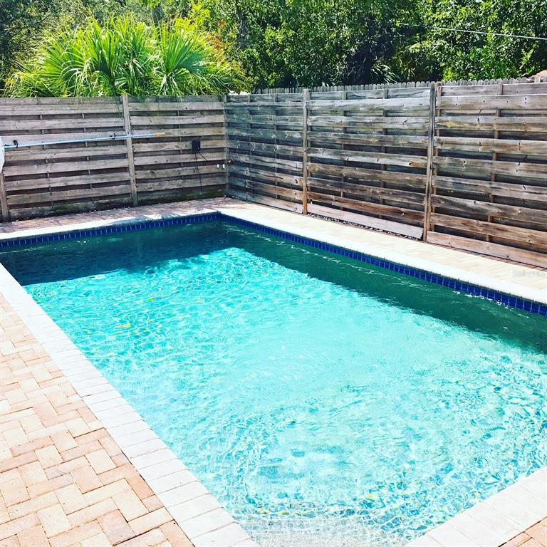 A rectangular swimming pool is surrounded by a brick patio and a wooden privacy fence — 2043 ROSELAWN STREET, SARASOTA, FL