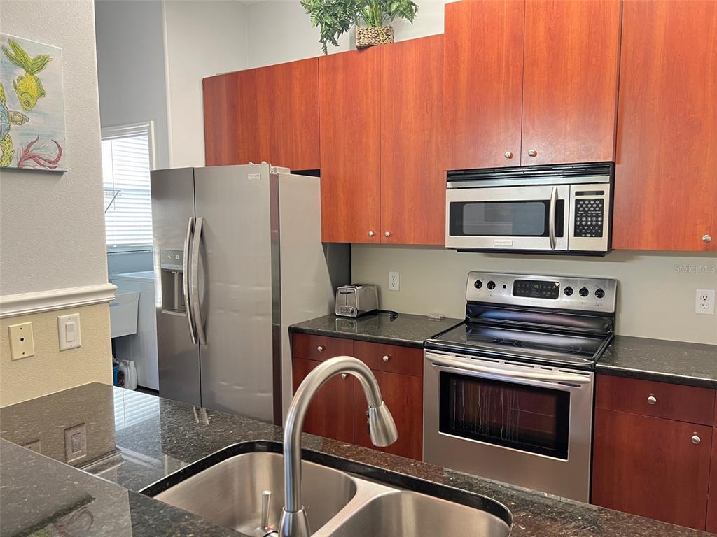 A kitchen features wood cabinets, stainless steel appliances, and dark granite countertops — 2043 ROSELAWN STREET, SARASOTA, FL