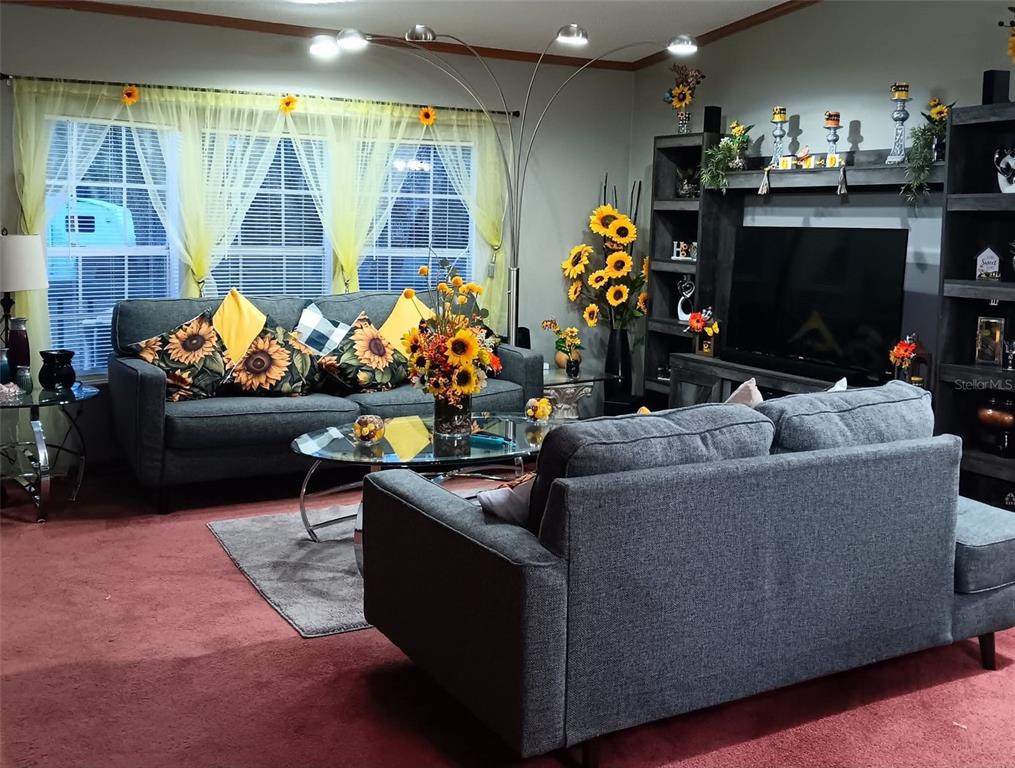 A living room features two gray sofas, a glass coffee table, and sunflower-themed decor — 9070 SE 196TH TERRACE, OCKLAWAHA, FL