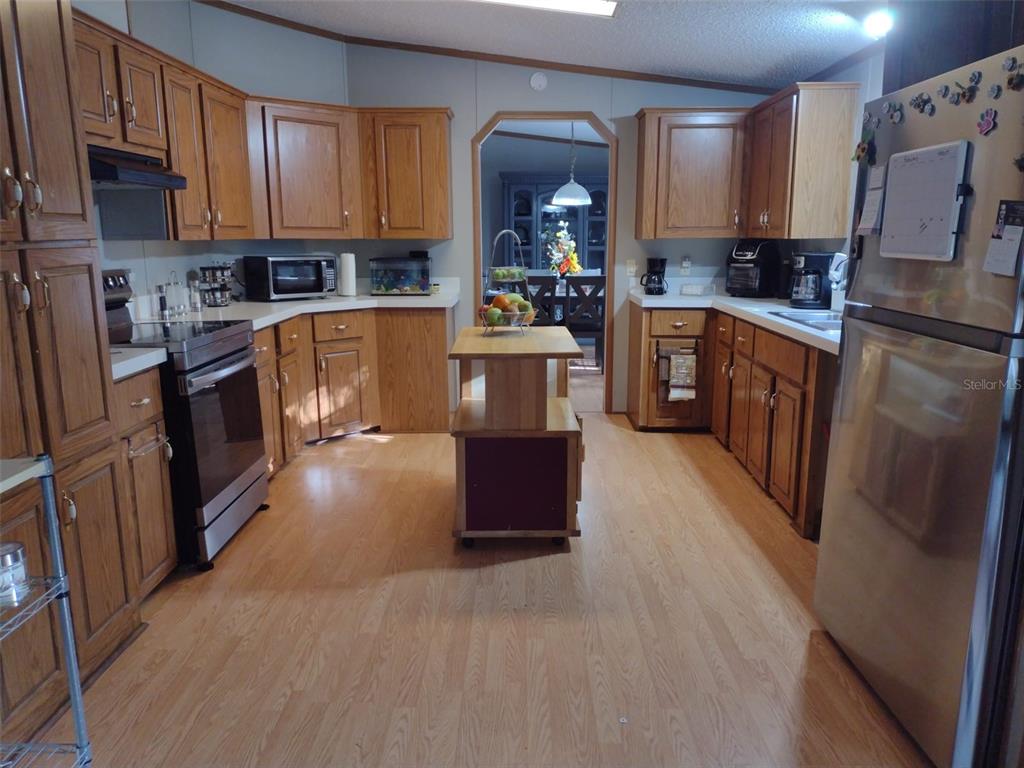 A kitchen with wood cabinets, stainless steel appliances, and a central rolling island — 9070 SE 196TH TERRACE, OCKLAWAHA, FL