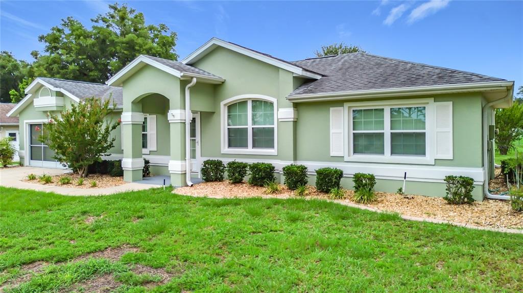 A light green single-story house with white trim, a covered entryway, and a grassy yard — 4771 NW 30TH PLACE, OCALA, FL