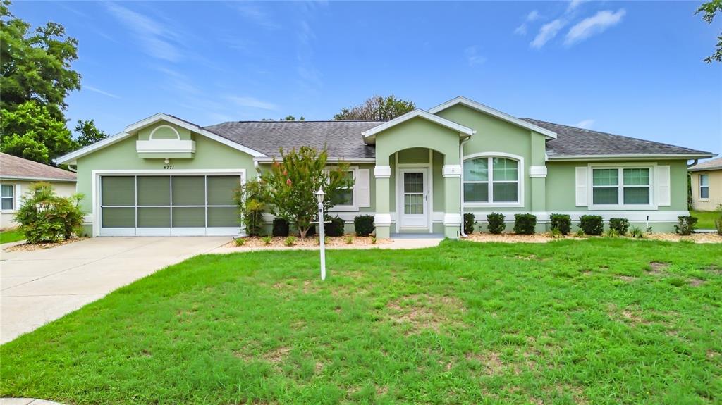 A single-story house with light green siding, a white garage door, and a front lawn — 4771 NW 30TH PLACE, OCALA, FL