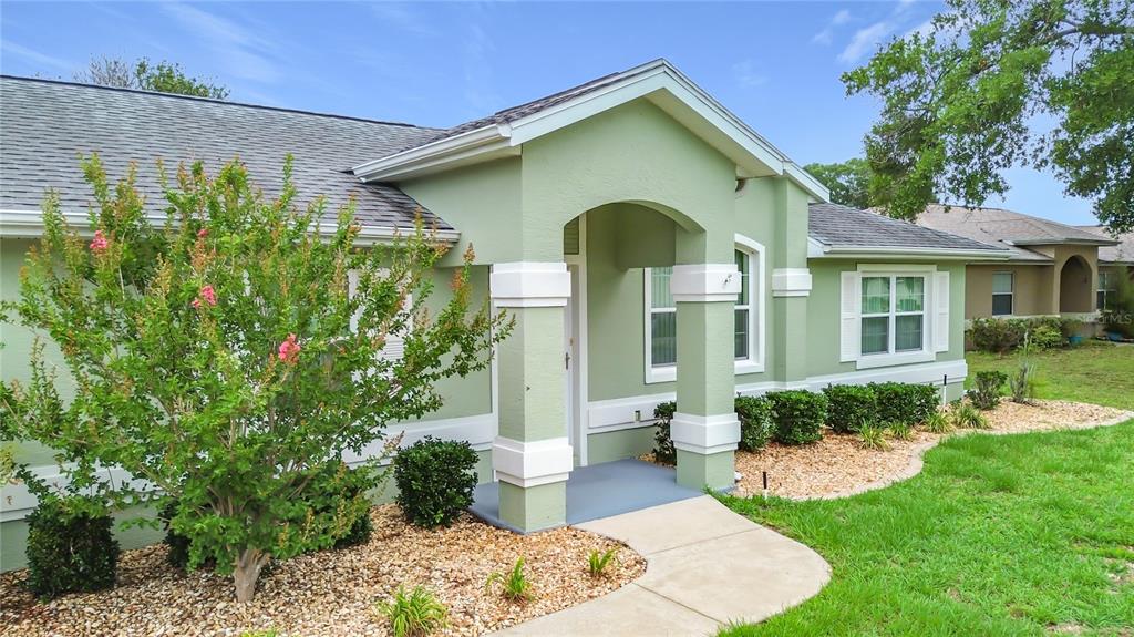 A light green single-story house features a covered entryway with white columns and landscaping — 4771 NW 30TH PLACE, OCALA, FL