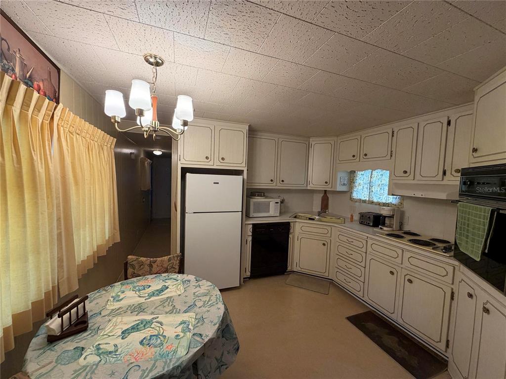 A kitchen with white cabinets, a white refrigerator, and a small dining table — 5121 9TH STREET W, BRADENTON, FL