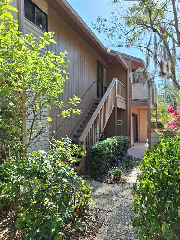An exterior view of a multi-story building with brown vertical siding and a wooden staircase — 1697 BROOKHOUSE CIRCLE UNIT 217, SARASOTA, FL