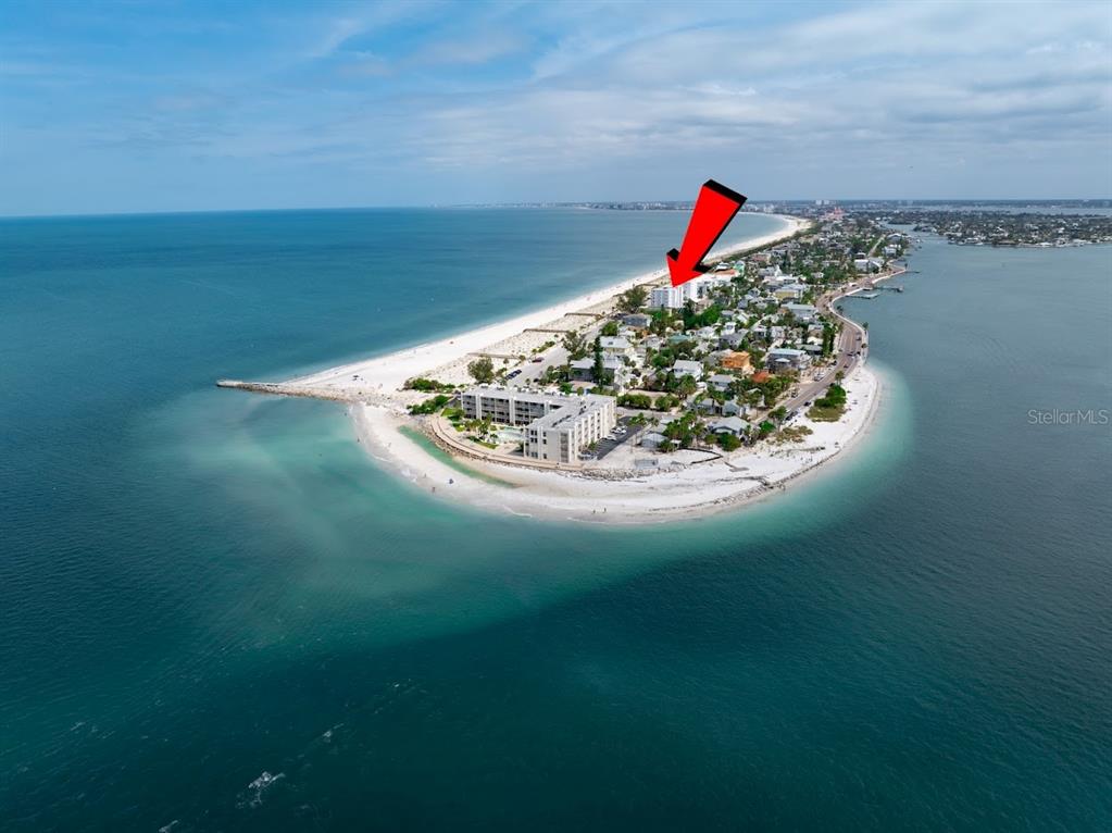 An aerial view shows a coastal barrier island with a red arrow pointing to a building — 403 GULF WAY UNIT 601, ST PETE BEACH, FL