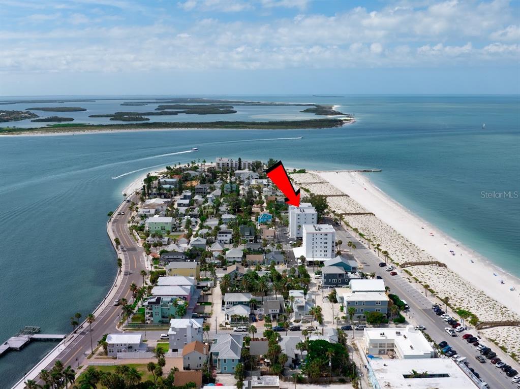 An aerial view shows a coastal neighborhood with a red arrow pointing to a condominium — 403 GULF WAY UNIT 601, ST PETE BEACH, FL